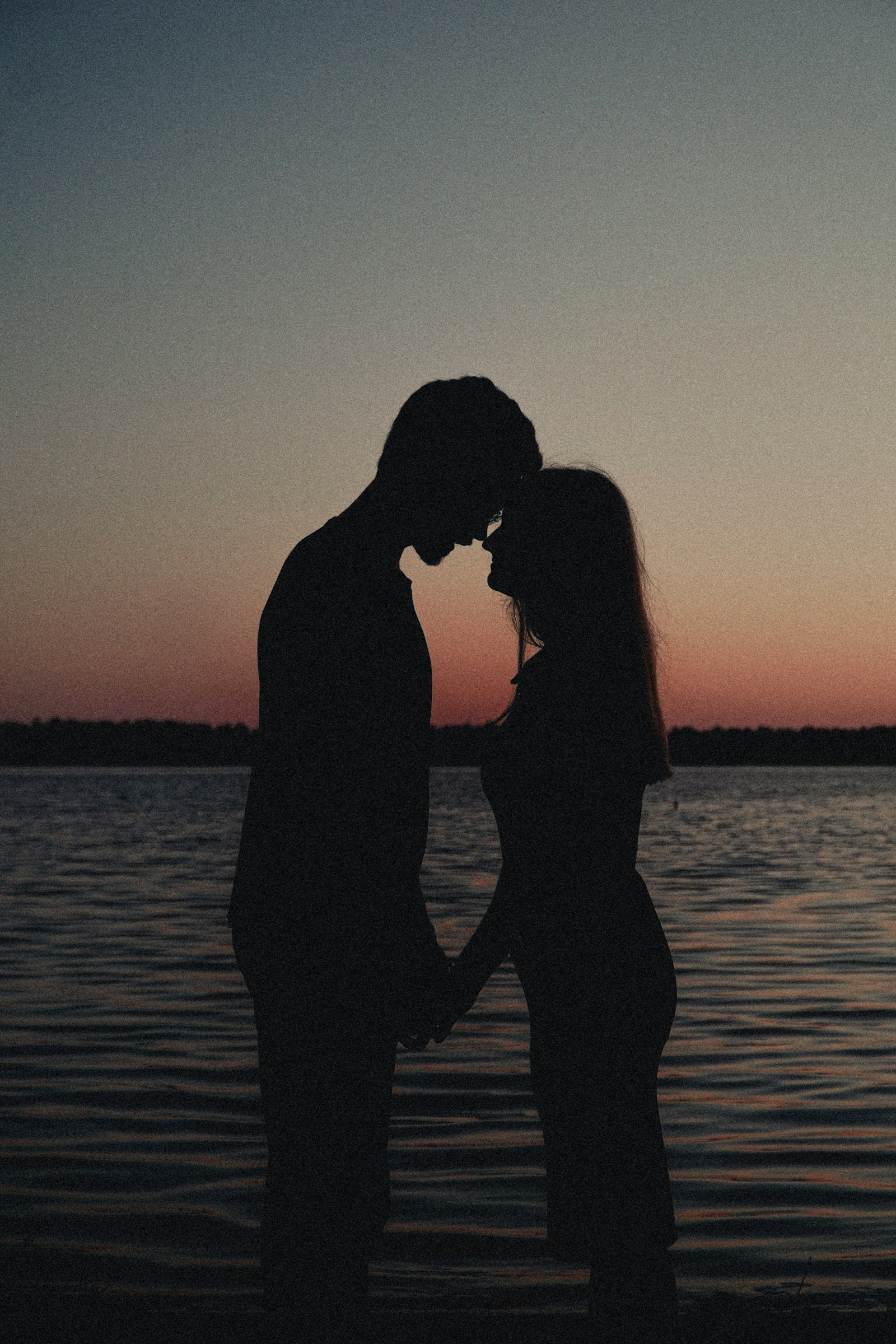 Couple holding hands at sunset by the water