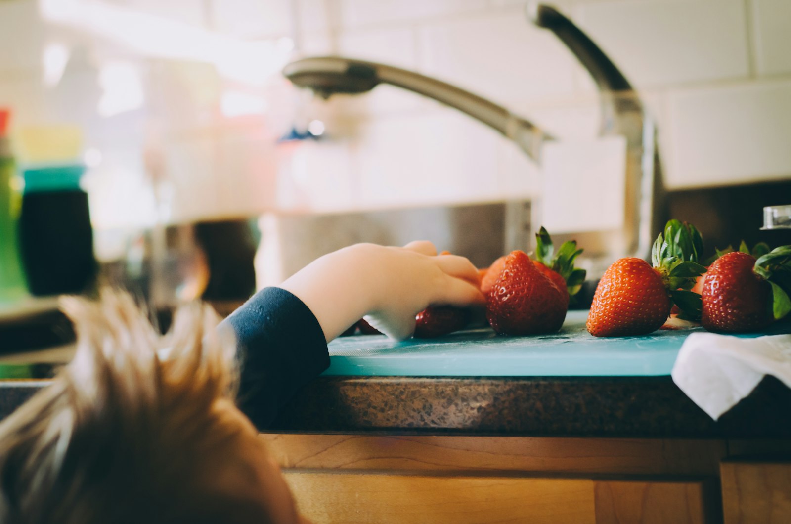 Child picking strawberries in a kitchen